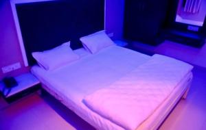 Hotel 7 Seas في Mundra: سرير بشرشف ووسائد بيضاء في الغرفة