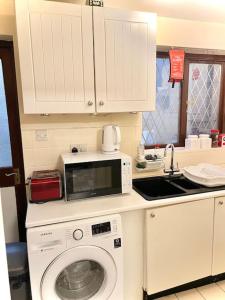 a kitchen with a washing machine and a microwave at Cosy 2 bedroom Detached House in Central London in London