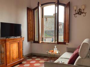 a living room with a couch and a tv and a window at House with a view in Tuscany in San Gusmè