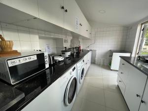 a kitchen with a washing machine and a microwave at Owls Hostel Ildefonso in Porto