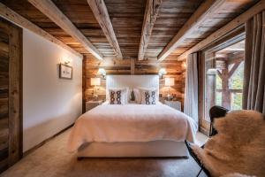 um quarto com uma cama e uma grande janela em Chalet La Ferme du Gron Les Carroz - BY EMERALD STAY em Les Carroz d'Arâches