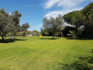 un parque con un parque infantil con árboles y un banco en Eden Jasmim by FHR, en Quarteira