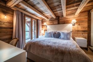 1 dormitorio con 1 cama grande y paredes de madera en Chalet La Ferme du Gron Les Carroz - BY EMERALD STAY, en Les Carroz d'Araches