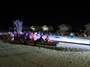 Desert island Camp & Resort Jaisalmer في Sām: مجموعة من الناس جالسين على حلبة ليل