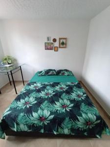 a bedroom with a bed with a green floral bedspread at Agradable Apto San Luis in Bucaramanga