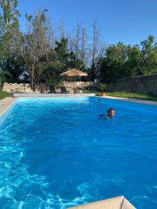 un hombre nadando en una piscina azul en Domaine la Boulinière - Le Sanglier, en Journet
