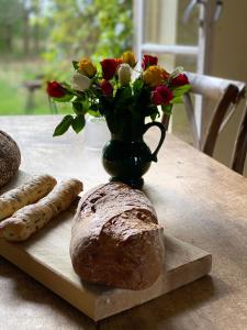 una mesa con un jarrón de flores y una barra de pan en Domaine la Boulinière - Le Sanglier, en Journet
