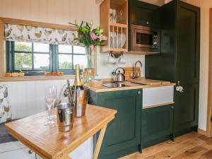 cocina con armarios verdes y mesa de madera en Poppie's Shepherds Hut, en Nottingham