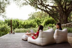 two girls sitting on a boardwalk reading books at Boutique Hotel - Poggio ai Santi in San Vincenzo