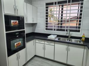 een keuken met witte kasten, een wastafel en een magnetron bij Jab Duplex X in Adentan