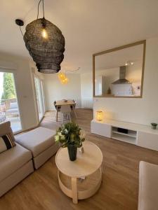 een woonkamer met een bank, een tafel en een spiegel bij Magnifique Appart rénové Evian vue Lac 8 pers in Évian-les-Bains
