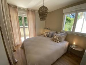 een slaapkamer met een wit bed met kussens en ramen bij Magnifique Appart rénové Evian vue Lac 8 pers in Évian-les-Bains