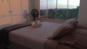 um quarto com uma cama, uma ventoinha e uma janela em Villa Candombá em Alto Paraíso de Goiás