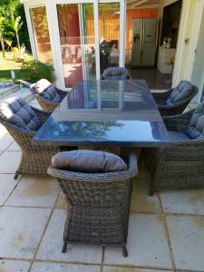 szklany stół z wiklinowymi krzesłami na patio w obiekcie Villa de 4 chambres avec piscine privee et wifi a Maule w mieście Maule