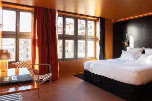 a hotel room with a bed and a desk and windows at Pilo Lyon in Lyon