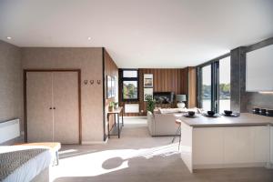 um quarto com uma cozinha e uma sala de estar com um sofá em Fabulous & New - Private Balcony - Station Nearby em Orpington