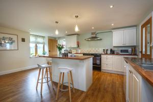 a kitchen with white cabinets and bar stools at Kings Beck Barn in Norwich