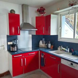 a kitchen with red cabinets and a sink and a window at Chambre chez l habitant 2 in Moumour