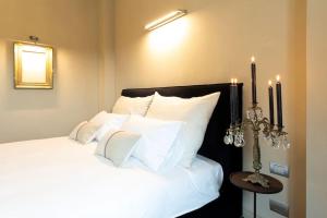 1 dormitorio con 1 cama con almohadas blancas y velas en L'Attico vicinissimo all'Ospedale di Cuneo con grande terrazzo en Cuneo
