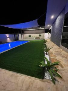 a swimming pool with a green lawn in a building at Moon light in Sharīyah