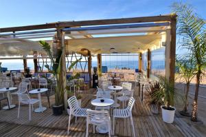 un restaurante con mesas y sillas blancas en una terraza en Villa Salamandre 10 people Costa Brava, en Maçanet de la Selva
