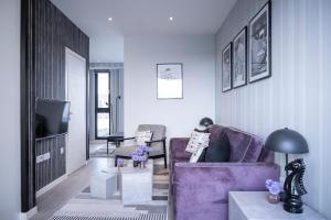 uma sala de estar com um sofá roxo e uma televisão em NEW & Spacious - Private Balcony - Station Nearby em Farnborough