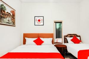2 bedden in een kamer met rode en witte kussens bij The Homey Rooms and Tours in Yogyakarta