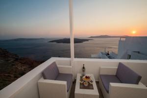 a balcony with chairs and a table with a view of the ocean at Corrado Caldera Apartments in Fira