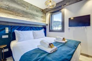 a bedroom with a blue and white bed with towels at ECHO DU PLENEY B203: Incroyable 4 chambres neuf à 150m de la télécabine de Super-Morzine in Morzine