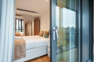 um quarto com uma cama e uma porta de vidro deslizante em Paddington Basin View Apartment em Londres