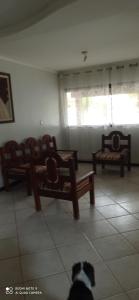 a dog is sitting in a room with benches at Casa de praia in Salvador