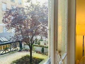 パリにあるDream Dwell Paris-Cozy historic appartement near Exelmans in 16th District Parisの中庭の木の景色を望む窓