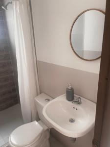 y baño con aseo, lavabo y espejo. en Apartamento 202 Entero en Montería