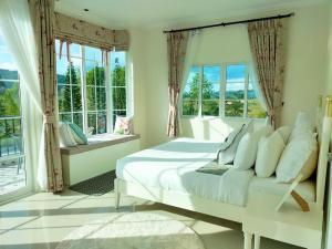 ein weißes Schlafzimmer mit großem Bett und Fenstern in der Unterkunft Misty English Cottage in Ban Non Na Yao