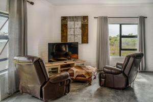 sala de estar con 2 sillas y TV en SkatKus Eco Estate, en Stilbaai-Wes