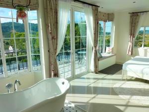 ein Bad mit einer Badewanne, einem Bett und Fenstern in der Unterkunft Misty English Cottage in Ban Non Na Yao + 104 Fotos
