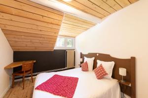 1 dormitorio con cama, techo de madera y escritorio en LOGIS Hôtel Restaurant La Vigotte, en Girmont-Val-dʼAjol