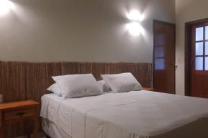a bedroom with a bed with white sheets and pillows at Casa Pequizeiro in Pirenópolis