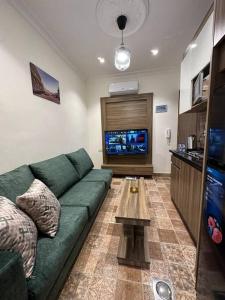 uma sala de estar com um sofá verde e uma televisão em 3/ Antica jabalal-lwebdeh em Amã