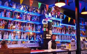 a man standing behind a bar with bottles of alcohol at Full Moon Central Party Hotel in Ko Phangan