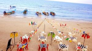 a beach with tables and chairs and boats in the water at Full Moon Central Party Hotel in Ko Phangan
