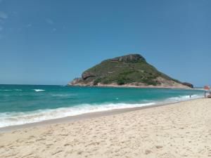 a view of a beach with a hill in the background at Apartamento super novo, ótima localização na praia do Recreio! in Rio de Janeiro