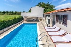 a swimming pool with lounge chairs next to a house at Villa Gortan - Pool house for 7 guests near Pula Istria - Ferienhaus Istrien in Marčana