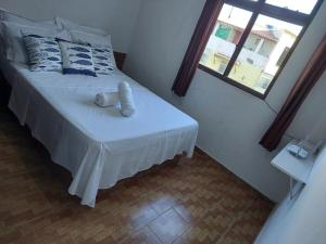 a bedroom with a white bed with a window at MIRANTE DA PRAINHA in Arraial do Cabo