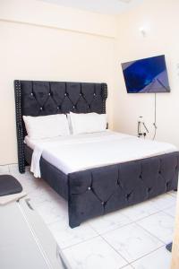 - un grand lit avec une tête de lit noire dans la chambre dans l'établissement The Nest Studio Apartment in Bamburi Mombasa, à Mombasa