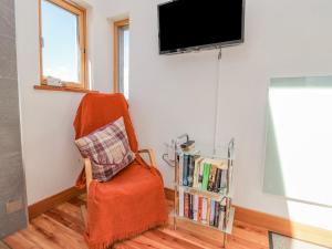 uma sala de estar com uma cadeira e uma televisão de ecrã plano em Easter Blervie em Forres