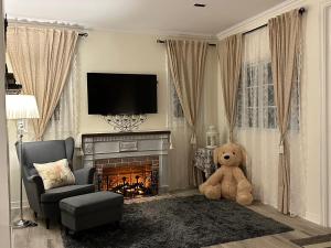 ein Wohnzimmer mit einem Teddybär, der vor einem Kamin sitzt in der Unterkunft Misty English Cottage in Ban Non Na Yao