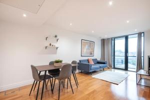 uma sala de estar com uma mesa e cadeiras e um sofá em Paddington Basin View Apartment em Londres