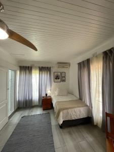 una camera da letto con letto e finestre con tende di Groenewald's Haven a Nelspruit
