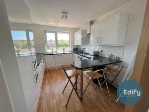 a kitchen with white cabinets and a table and chairs at 2 Br Flat Free Parking Great Location in Southampton